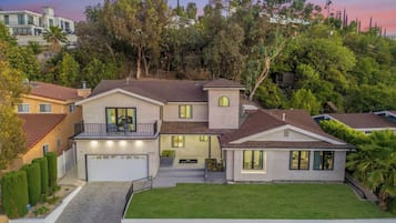 A two-story house with a garage, a balcony, and a well-maintained lawn.