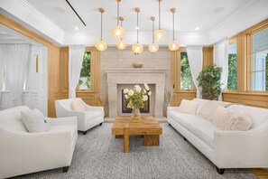 Amplia sala de estar con sofás blancos, una mesa de centro de madera y una chimenea.