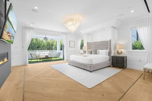 Un dormitorio amplio con una cama grande, una chimenea y vistas a un jardín exuberante.