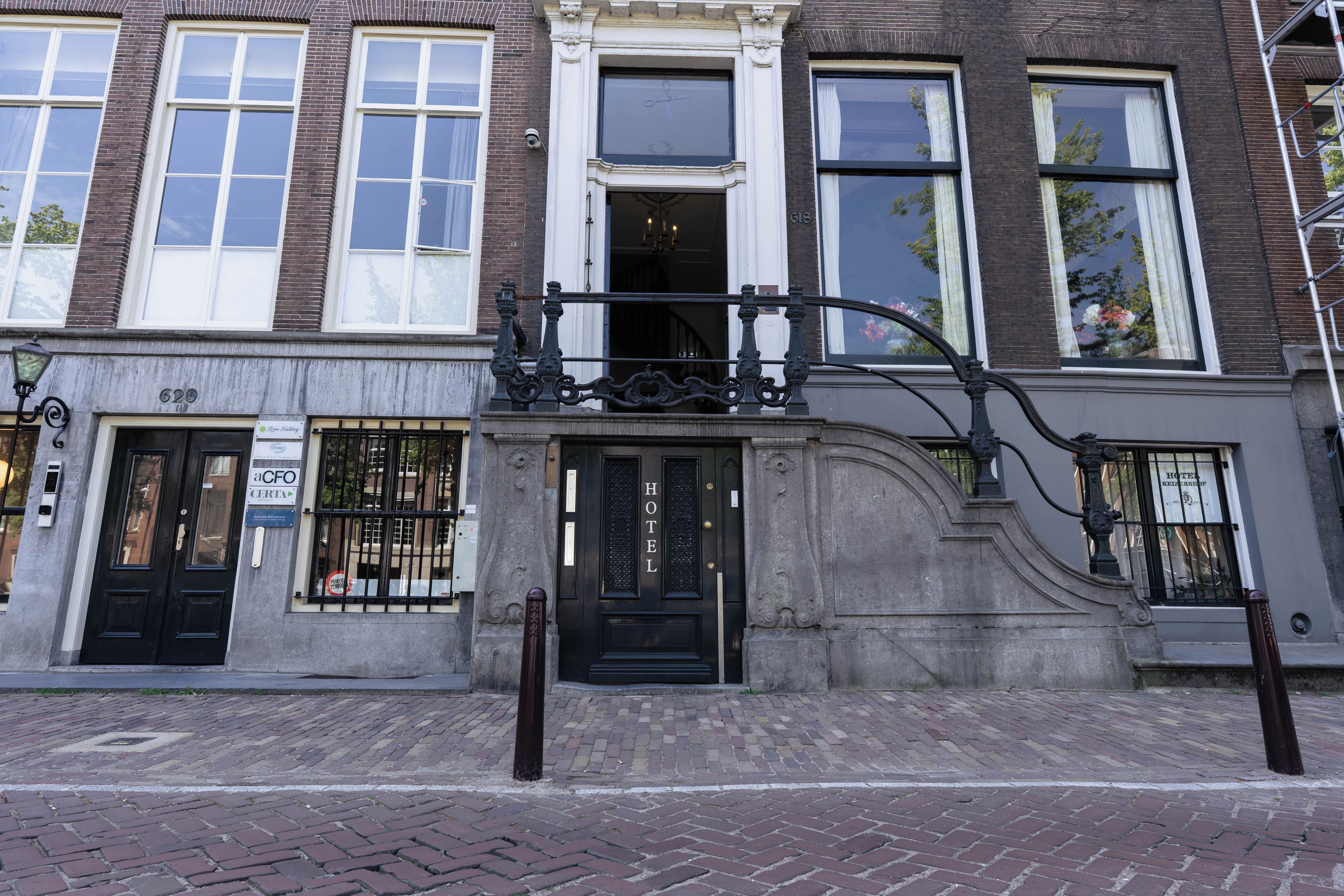 A historic building with a black entrance door, large windows, and a brick facade.