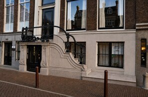 Un edificio histórico con una puerta de entrada negra y una escalera que conduce a ella, con un letrero que indica que es un hotel.