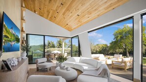 Ein modernes Wohnzimmer mit einem großen, weißen Ecksofa, einem runden Couchtisch und einer Holzbodenverkleidung.