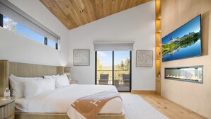 Ein modernes Schlafzimmer mit einem großen Bett, einem Kamin, einem Fernseher und einem Balkon mit Aussicht.