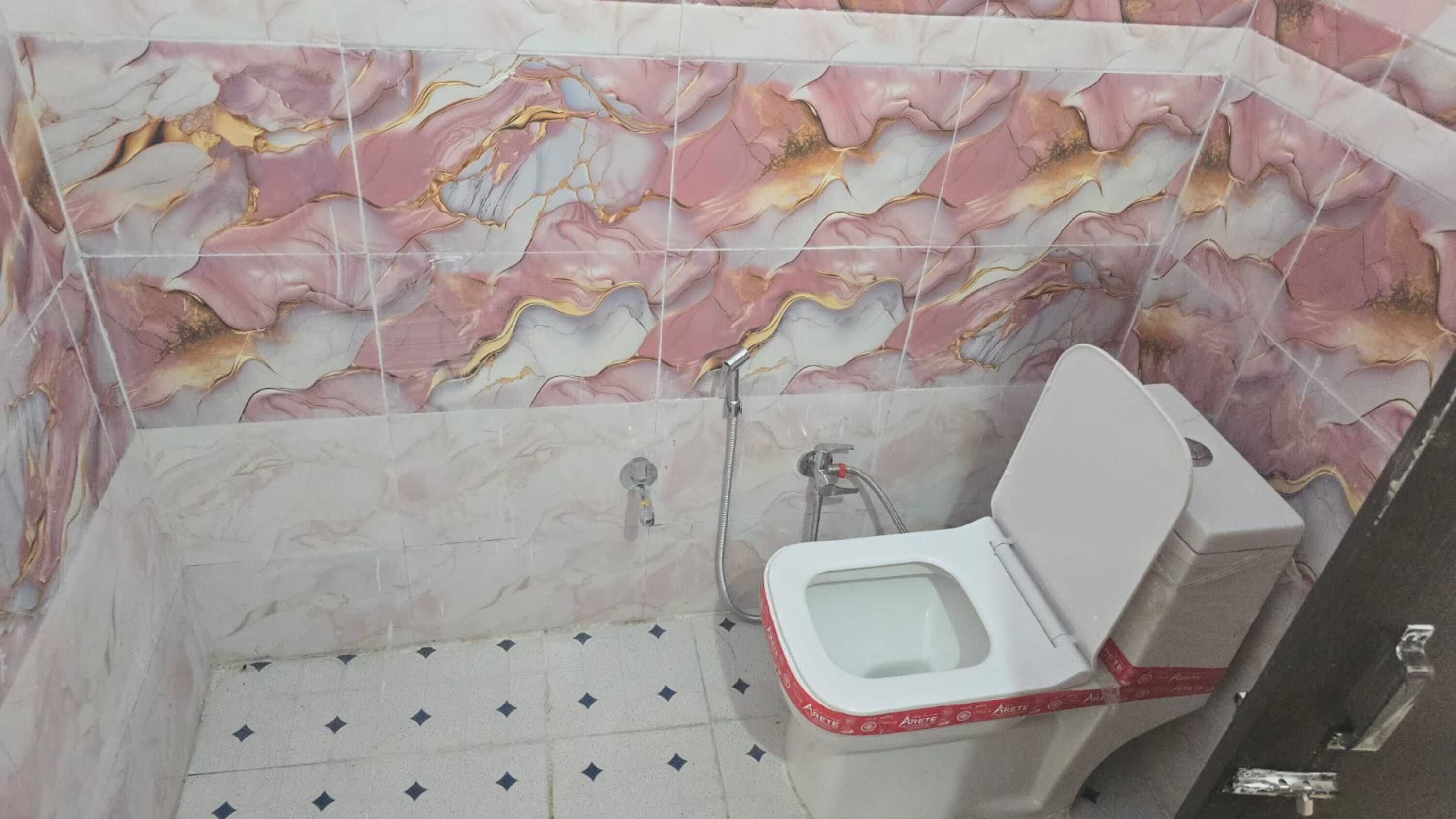 Une salle de bain avec un mur en marbre, des toilettes et une douche.