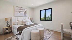 A bedroom with a large bed, two bedside tables, a window with a view, and a chair. - The Dona Modern (Studio City)