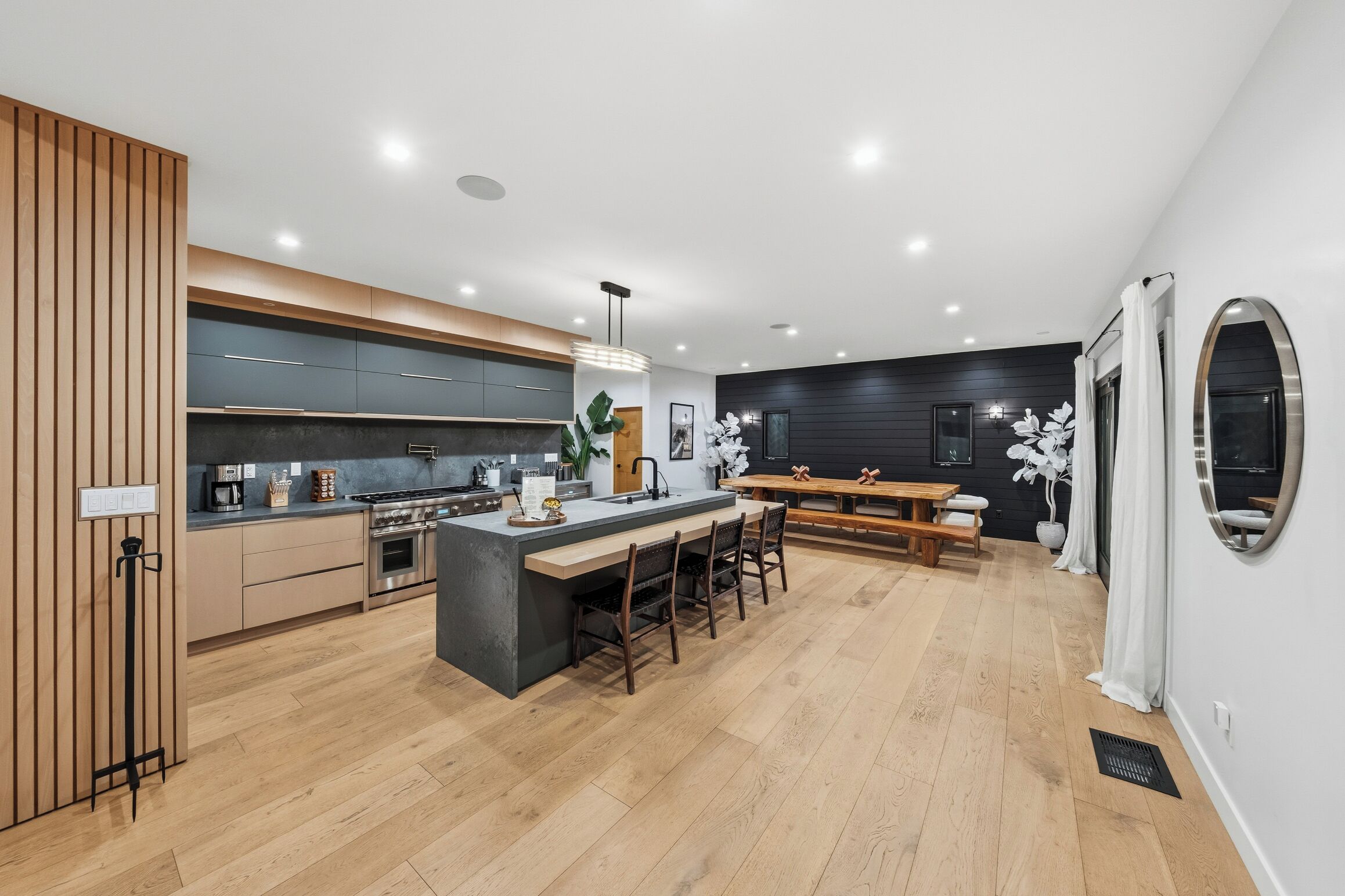 Cozinha moderna com ilha central, piso de madeira e área de refeições com banco.