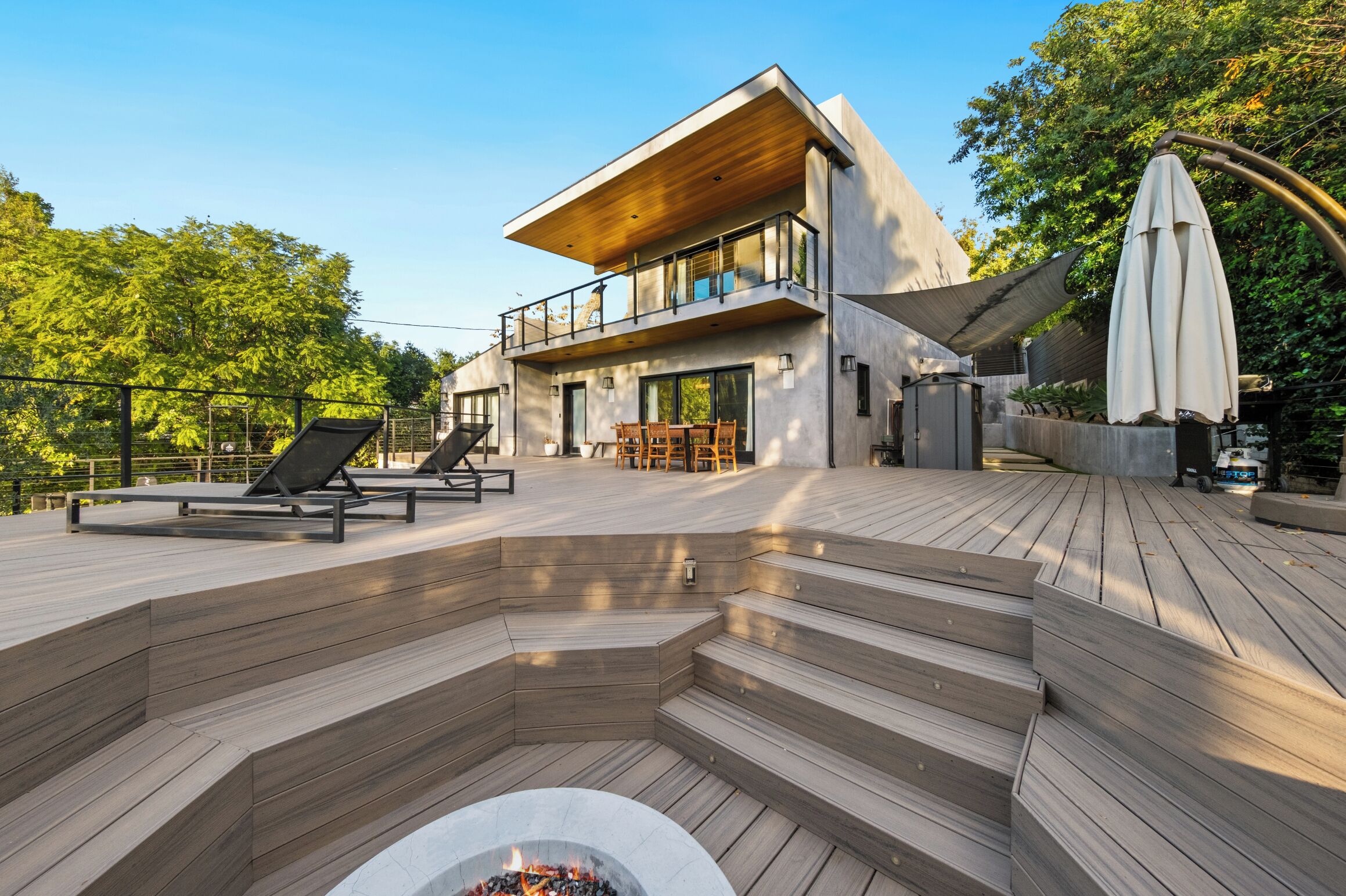 Uma casa moderna com um deck, área de estar externa e lareira.
