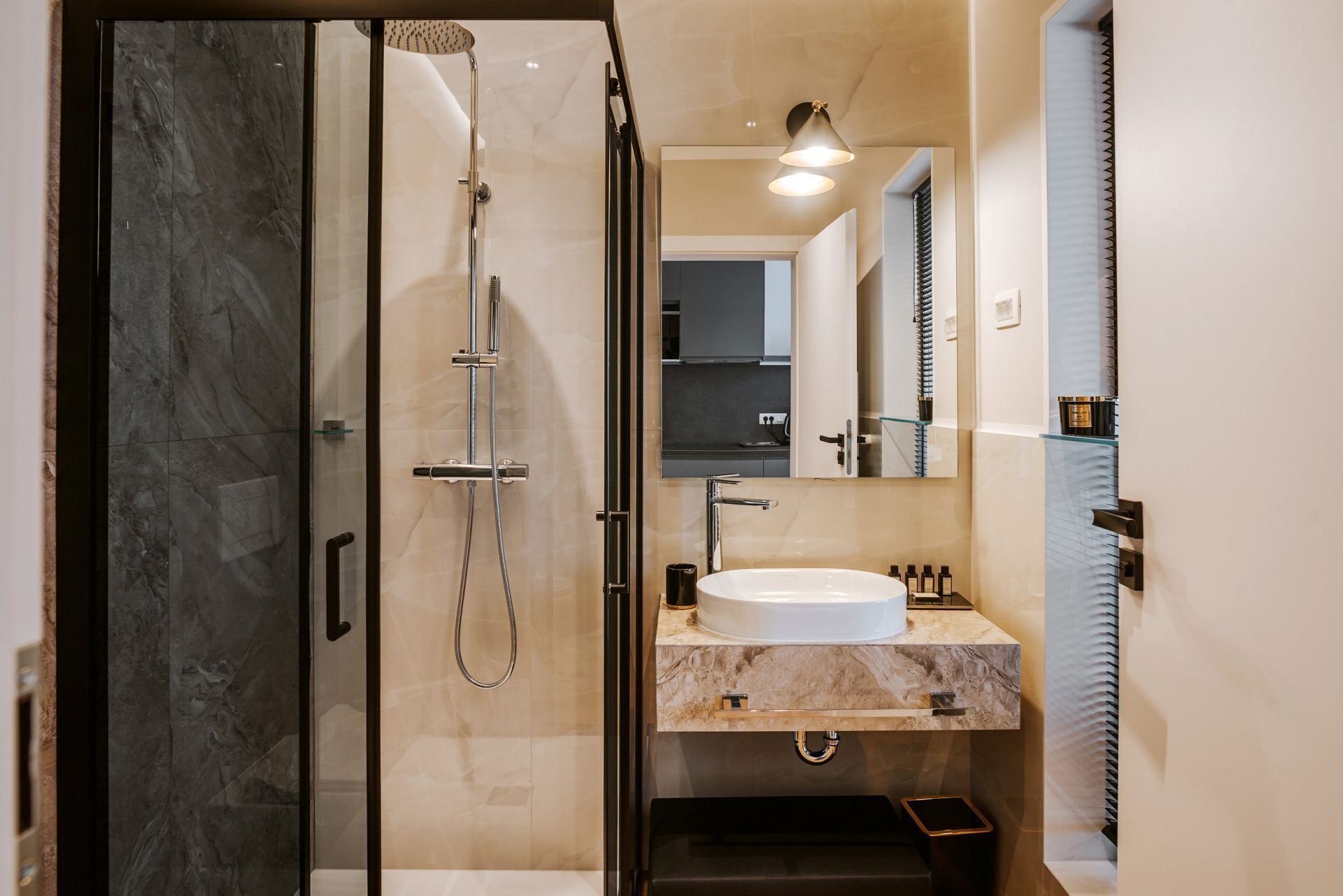 A modern bathroom with a glass shower enclosure, a white sink, and a mirror above the sink.