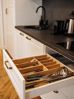 Un cajón de cocina con utensilios.