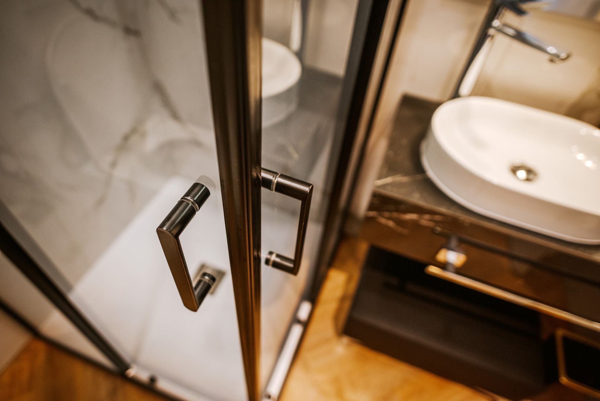 Baño con puerta de vidrio, lavamanos y espejo.