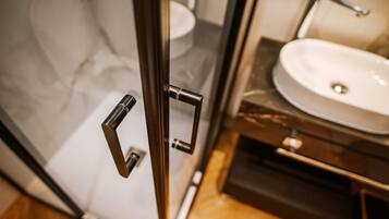Baño con puerta de vidrio, lavamanos y espejo.
