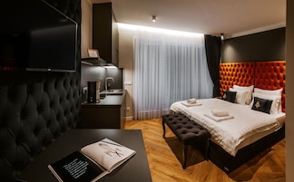 Una habitación de hotel moderna con una cama grande, un escritorio con un libro, una cafetera y un televisor.