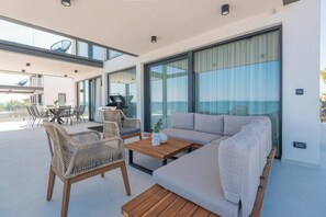 Ein modernes Wohnzimmer mit einer Couch, Korbstühlen, einem Holztisch und einem Esstisch.