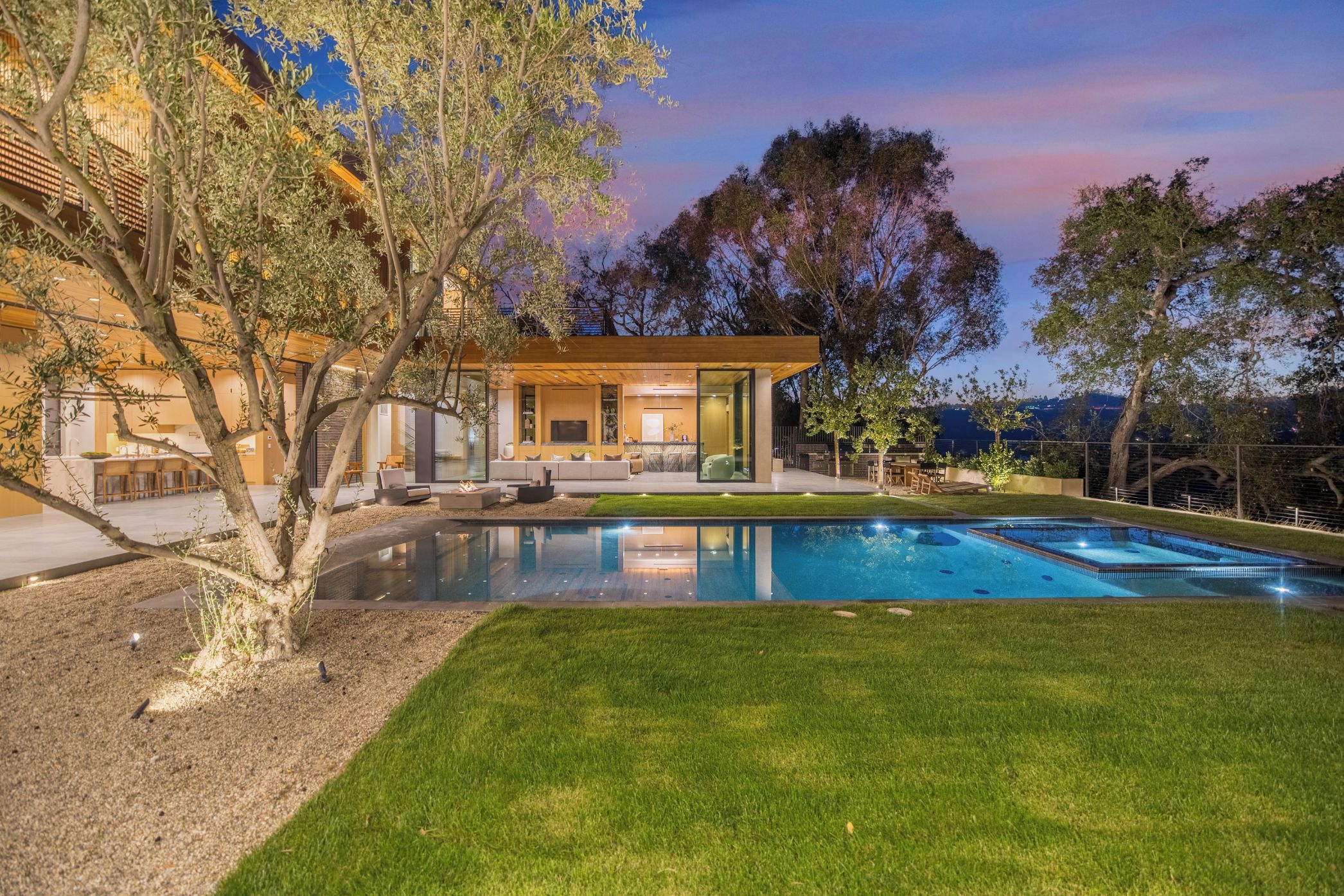 A modern house with a pool, outdoor seating, and a view of the surrounding landscape.