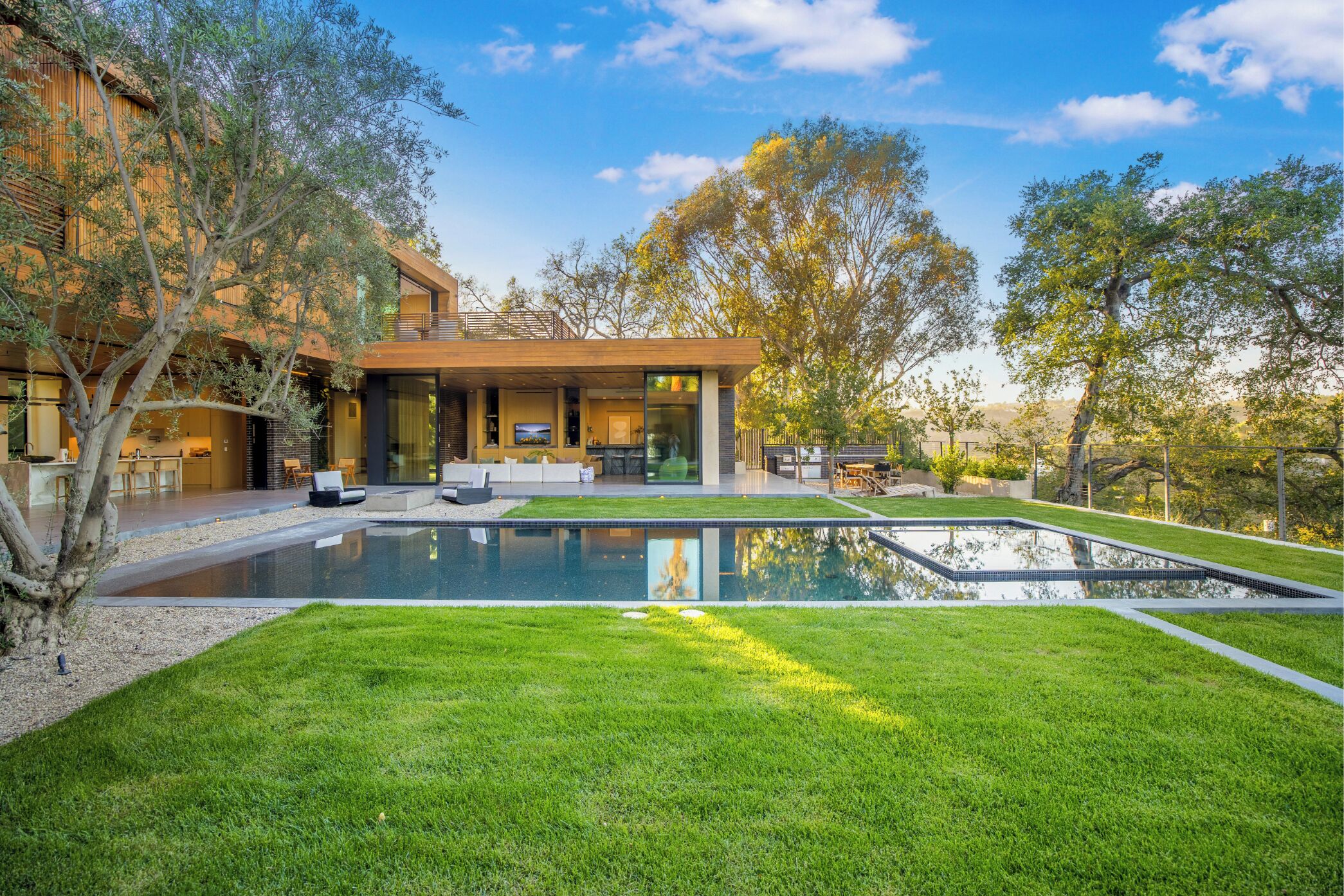 A modern house with a swimming pool, outdoor seating, and a well-maintained lawn.
