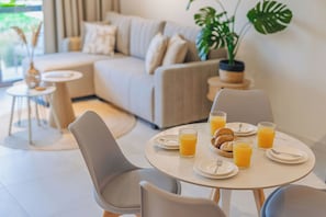 Ein Essbereich mit einem runden Tisch, gedeckt für das Frühstück, einschließlich Tellern, Gläsern mit Orangensaft und Gebäck.