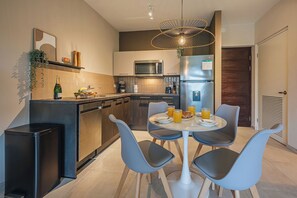 Een moderne keuken met een eethoek, inclusief een magnetron, koelkast en een eettafel met stoelen.