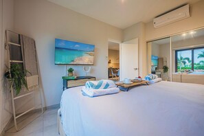 Een hotelkamer met een bed, een televisie, een plant, een handdoek en een raam met uitzicht.