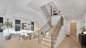 A modern interior with a wooden staircase, a dining area, and a large potted plant. - Kraft Villa (North Hollywood)