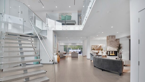 A spacious, modern interior with a staircase leading to a mezzanine, a fireplace, and a well-lit living area. - Colgate Vantage (Los Angeles)