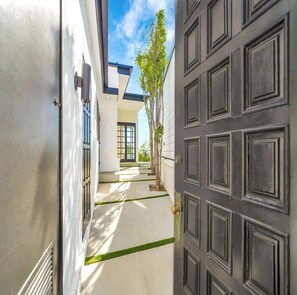 A modern house with a dark wooden door, a narrow pathway, and a small tree. - Skyview Estate (West Hollywood)