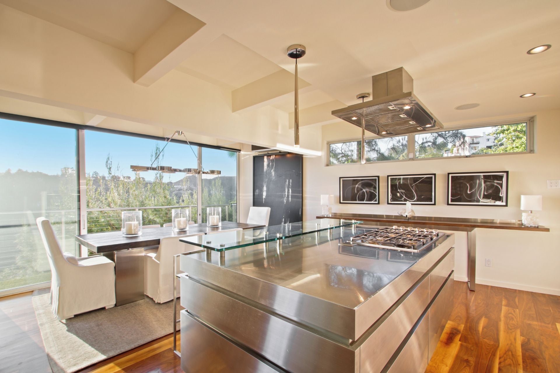 A modern kitchen with a glass island, stainless steel appliances, and a large window overlooking a scenic view.