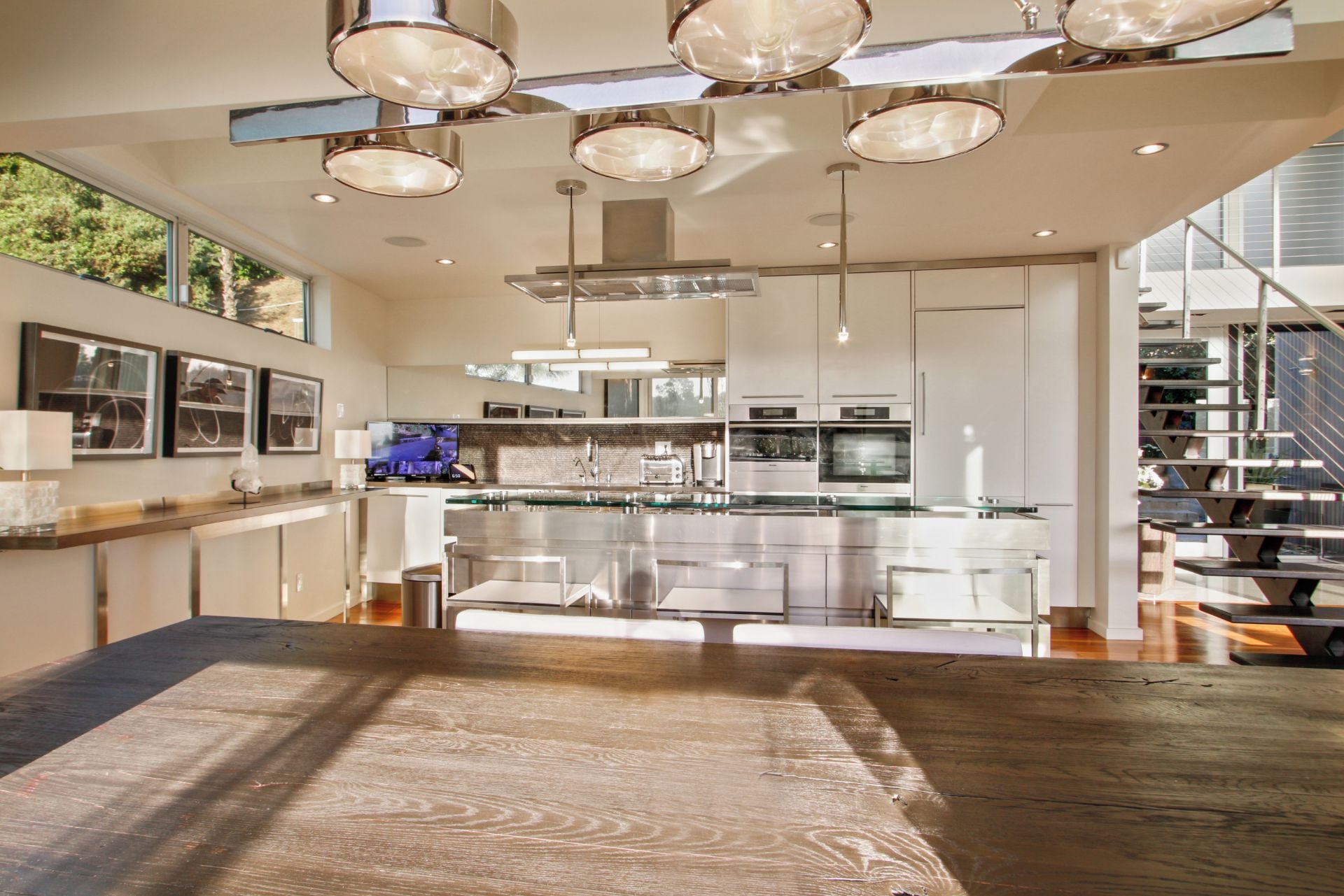 A modern kitchen with stainless steel appliances, a glass island, and pendant lighting.