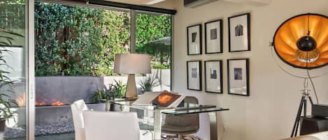 Una sala de estar moderna con una mesa de vidrio, muebles blancos y un amplio ventanal con vistas a la vegetación.