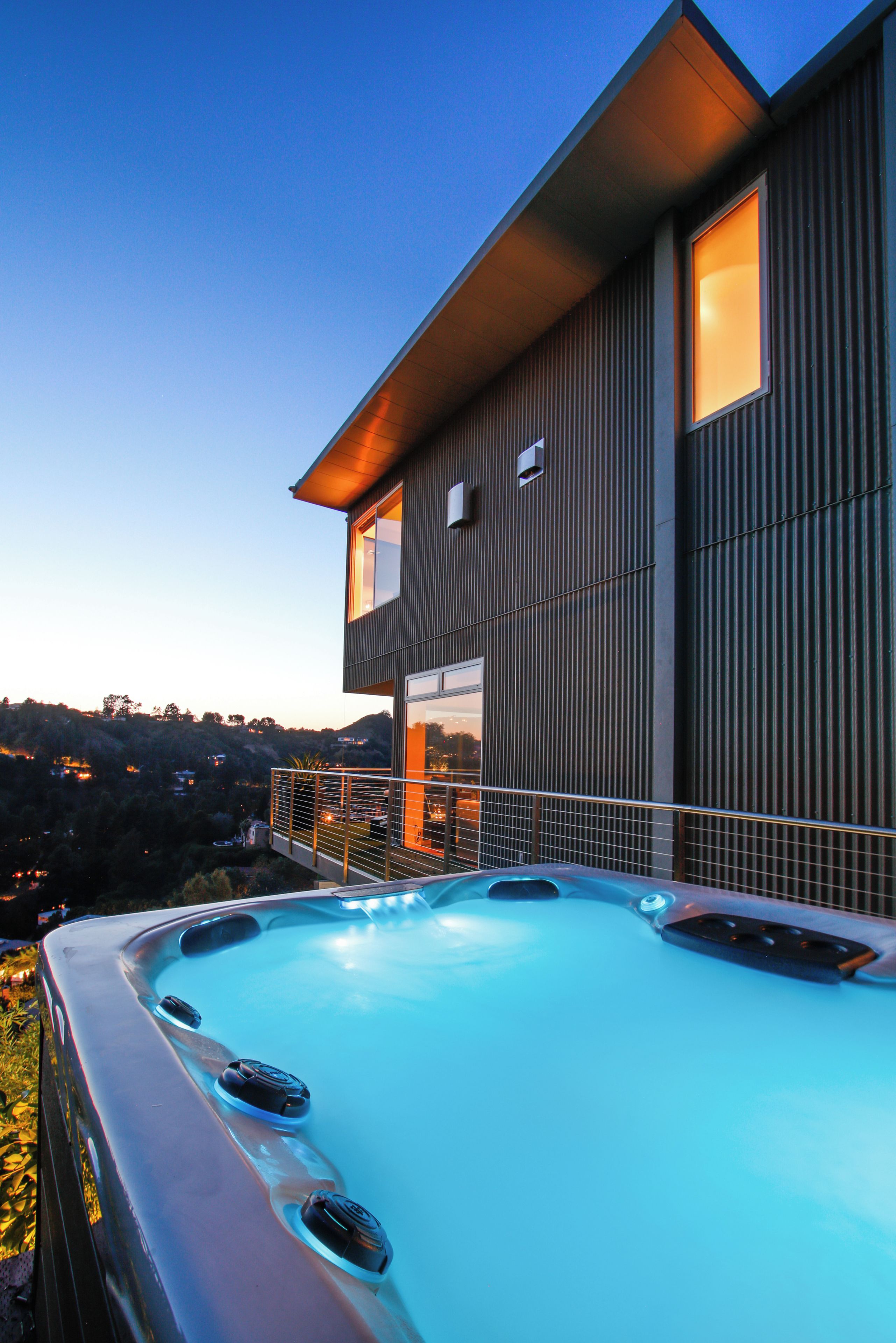 A modern two-story house with a hot tub on the balcony.