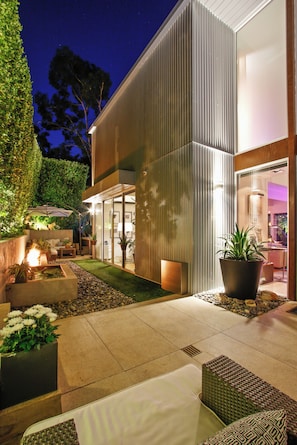 A modern outdoor patio area with a fire feature, seating, and potted plants. - Beverly Horizon (Beverly Hills)