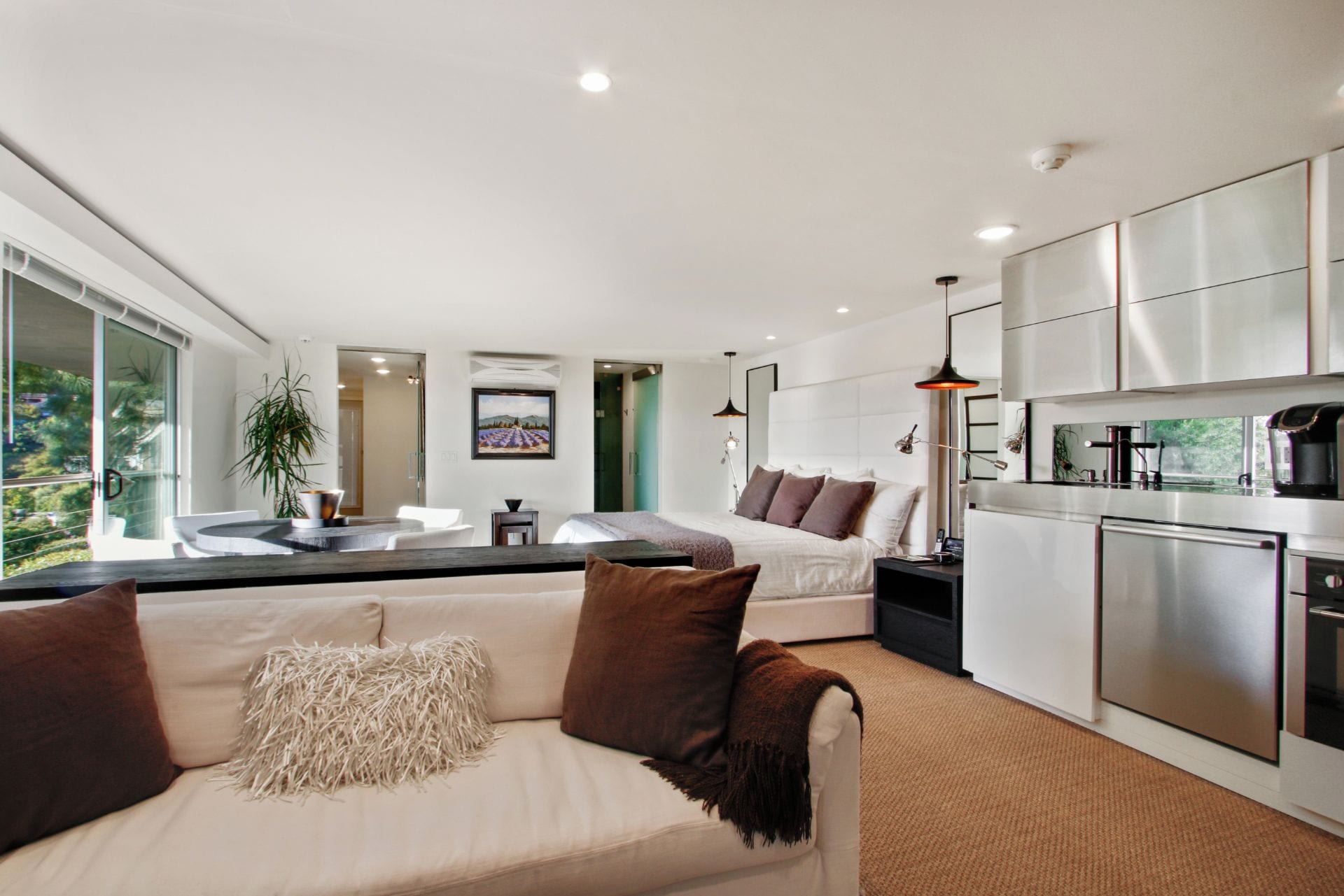 A modern interior with a living area featuring a sofa, a dining table, and a kitchen with stainless steel appliances.