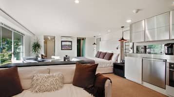 A modern interior with a living area featuring a sofa, a dining table, and a kitchen with stainless steel appliances.