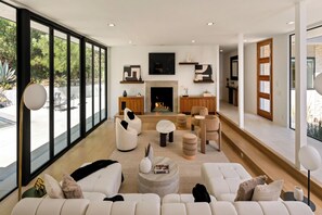 A modern living room with a fireplace, large windows, and a minimalist design. - Valea Estate (Beverly Hills)