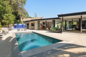 A modern house with a swimming pool, outdoor seating, and a covered patio area. - Valea Estate (Beverly Hills)