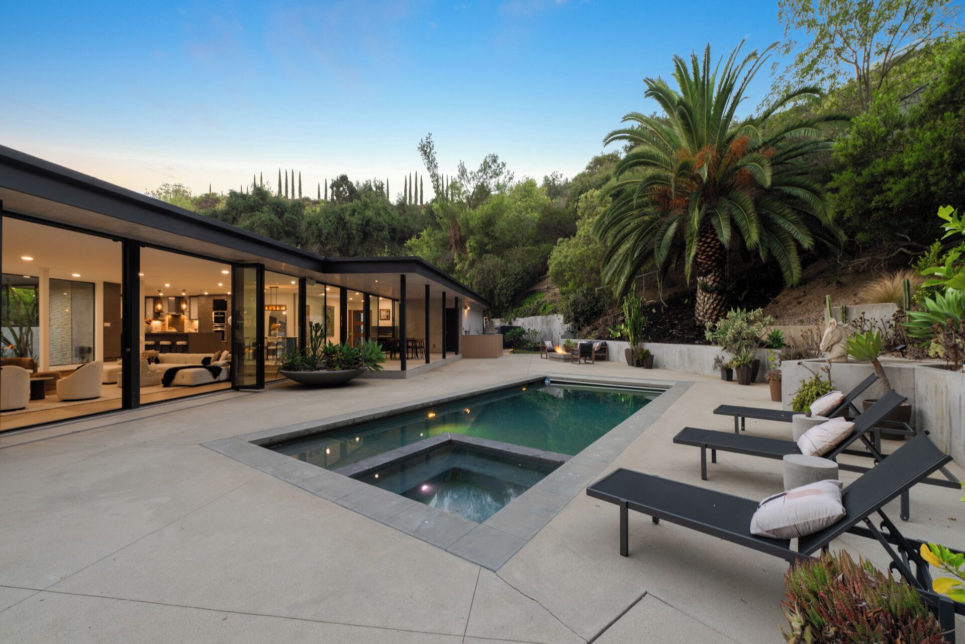 A modern house with a swimming pool, outdoor seating, and a lush garden.