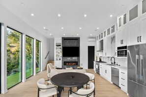 Una cocina moderna con armarios blancos, horno empotrado y refrigerador de acero inoxidable.