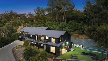 A modern two-story house with a large deck and a swimming pool.