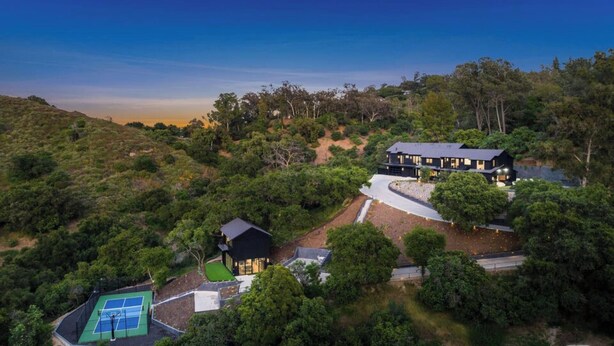 A modern house with a tennis court, surrounded by dense vegetation and hills. - Oak Haven Sanctuary (Studio City)