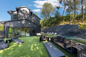 Un espacio exterior moderno con piscina, sillones de descanso y un amplio sofá.