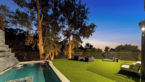 A backyard with a swimming pool, artificial grass, and a lounge area. - Oak Haven Sanctuary (Studio City)