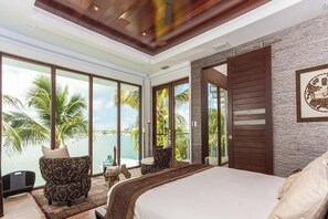 A bedroom with a large bed, a view of the sea, and a balcony with a chair. - Villa Teaka (Miami Beach)