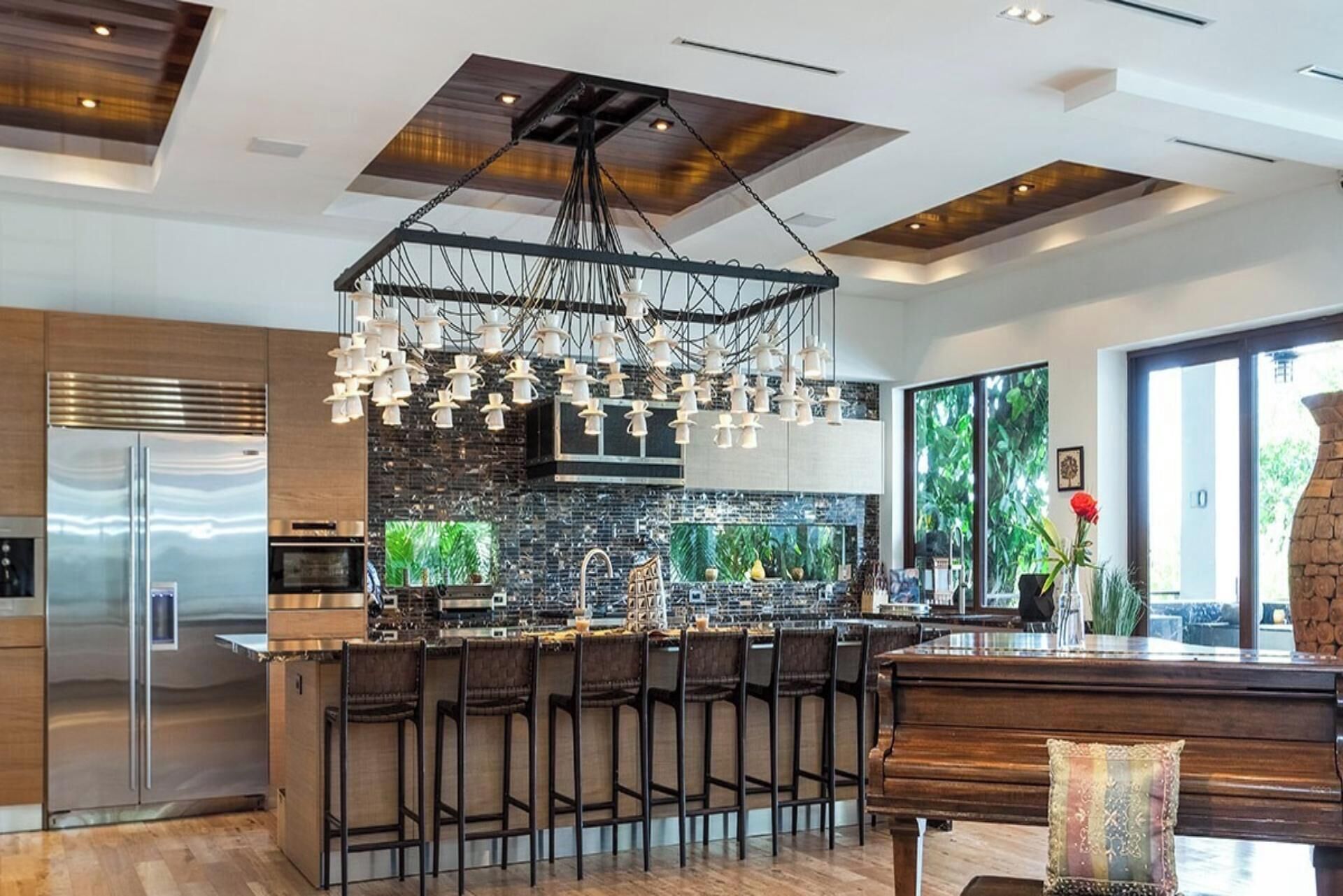 Cozinha moderna com ilha central, eletrodomésticos de aço inoxidável e luminária pendente.