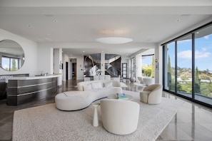 Una sala de estar moderna con un sofá curvo, una mesa de centro y un ventanal con vistas al exterior.