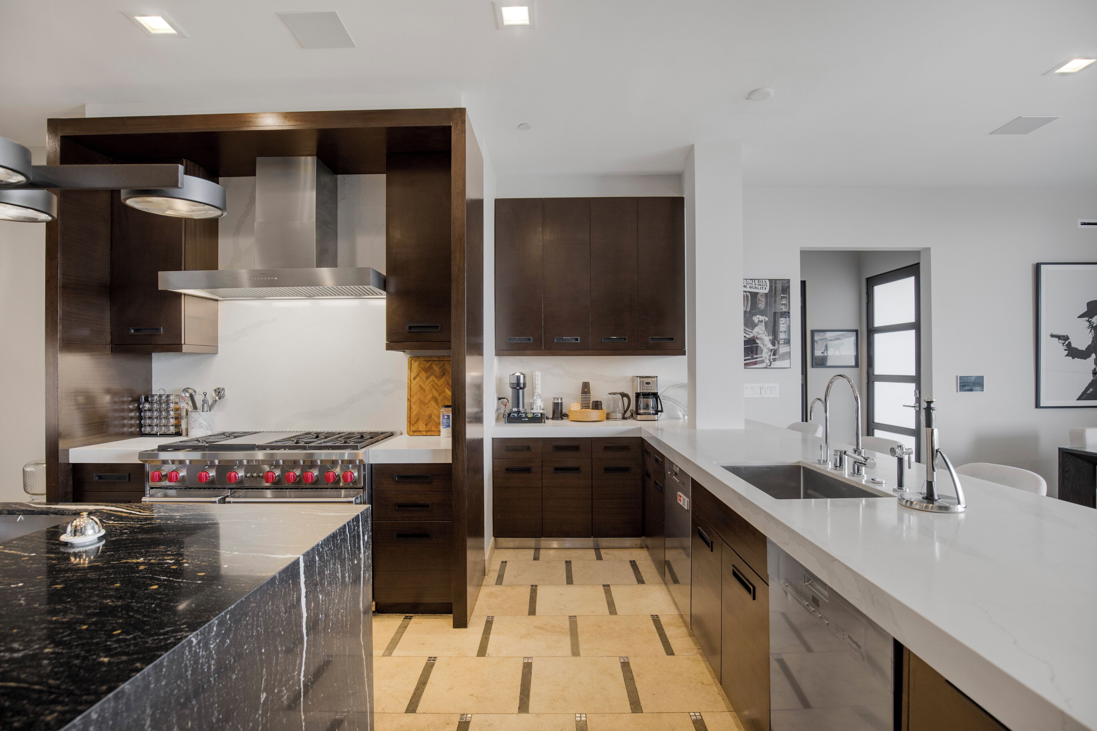 A modern kitchen with a central island, built-in oven, and stainless steel appliances.