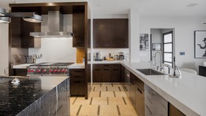 A modern kitchen with a central island, built-in oven, and stainless steel appliances. - Beverly Crest (Beverly Hills)