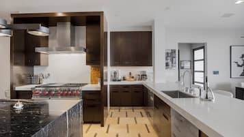 A modern kitchen with a central island, built-in oven, and stainless steel appliances.