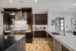 A modern kitchen with a central island, built-in oven, and stainless steel appliances. - Beverly Crest (Beverly Hills)
