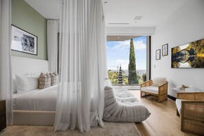 A bedroom with a bed, a large window, a chair, and a view of the outdoors. - Beverly Crest (Beverly Hills)