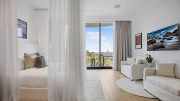 A modern living room with a sofa, a bed, and a large window with a view of a building.
