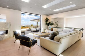 A modern living room with a large sofa, a coffee table, and a seating area with a view of the cityscape. - Saint Ives Reserve (West Hollywood)